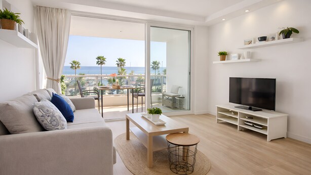 En moderne stue med sofa, TV og balkon med havudsigt.