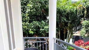 A balcony with two wicker chairs and a small round table, surrounded by a metal railing and potted plants. - UBUMWE APARTHOTEL KIGALI (Kigali)