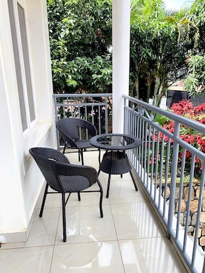 A balcony with two wicker chairs and a small round table, surrounded by a metal railing and potted plants. - UBUMWE APARTHOTEL KIGALI (Kigali)
