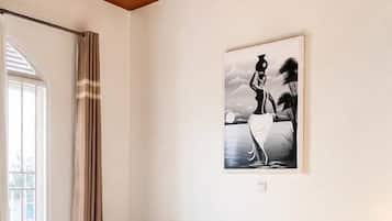 Ein Hotelzimmer mit Bett, Nachttisch, Lampe und einem Fenster mit Vorhängen.