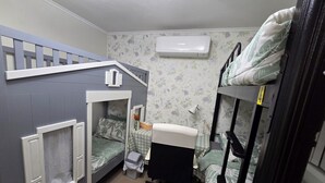 A compact room with a bunk bed, a desk, a chair, and an air conditioning unit.