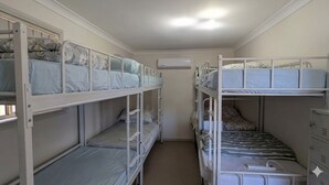 Kerrossängyllä varustettu huone, jossa on valkoinen katto, valkoinen seinä ja valkoinen ovi.