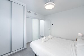 A modern hotel room with a large bed, a bedside table, a lamp, and a wardrobe. - Paloma Central Apartment (Nerja)