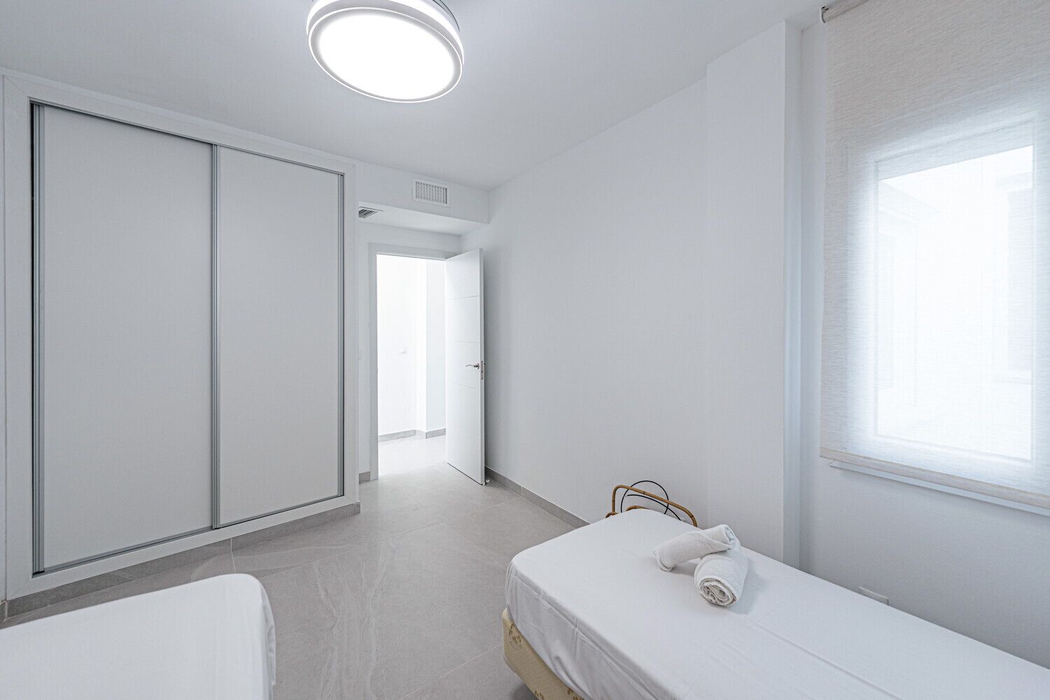 Ein schlicht eingerichtetes Schlafzimmer mit Bett, Kleiderschrank und Fenster.