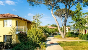A yellow building with a tiled roof, a pathway, and surrounding greenery. - Sea View Duplex for 8 on Var Coast (Six-Fours-les-Plages)