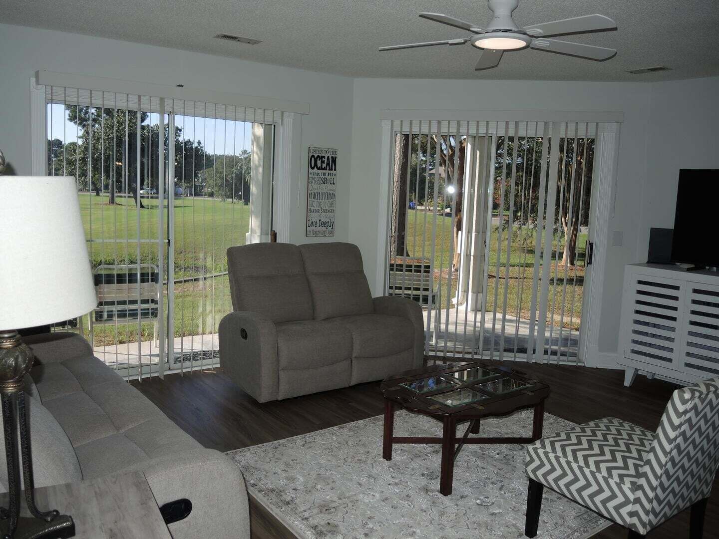 A living room with a sofa, armchair, coffee table, and a television.