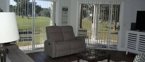 A living room with a sofa, armchair, coffee table, and a television.