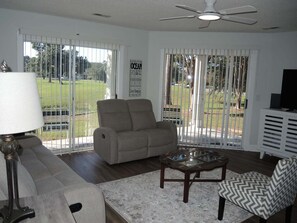 A living room with a sofa, armchair, coffee table, and a television. - 104 2 Bedroom Villa (Calabash)