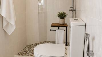 A bathroom with a toilet, shower, and a small table with a plant.