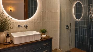 Une salle de bain avec un lavabo blanc, un meuble-lavabo en bois foncé et une douche dotée d’une porte en verre.