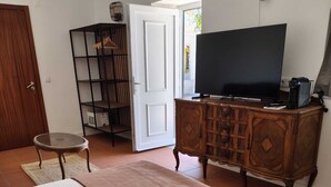 A bedroom with a bed, a television on a wooden cabinet, a small round table, and a wardrobe. - Quinta dos Pilotos (Almada)