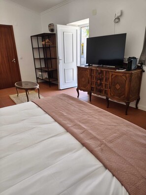 A bedroom with a bed, a television on a wooden cabinet, a small round table, and a wardrobe. - Quinta dos Pilotos (Almada)