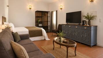 A modern hotel room with a bed, sofa, TV, and a cabinet with decorative items.