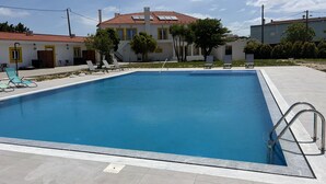 Una piscina rectangular con una escalera metálica en un lateral, rodeada por una solana con baldosas.