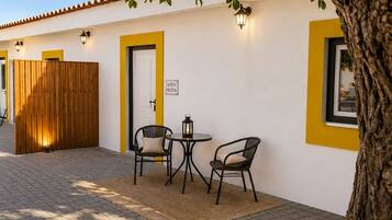 A courtyard with a wooden fence, a door labeled 'QUINTA PLOTS,' and two tables with chairs.