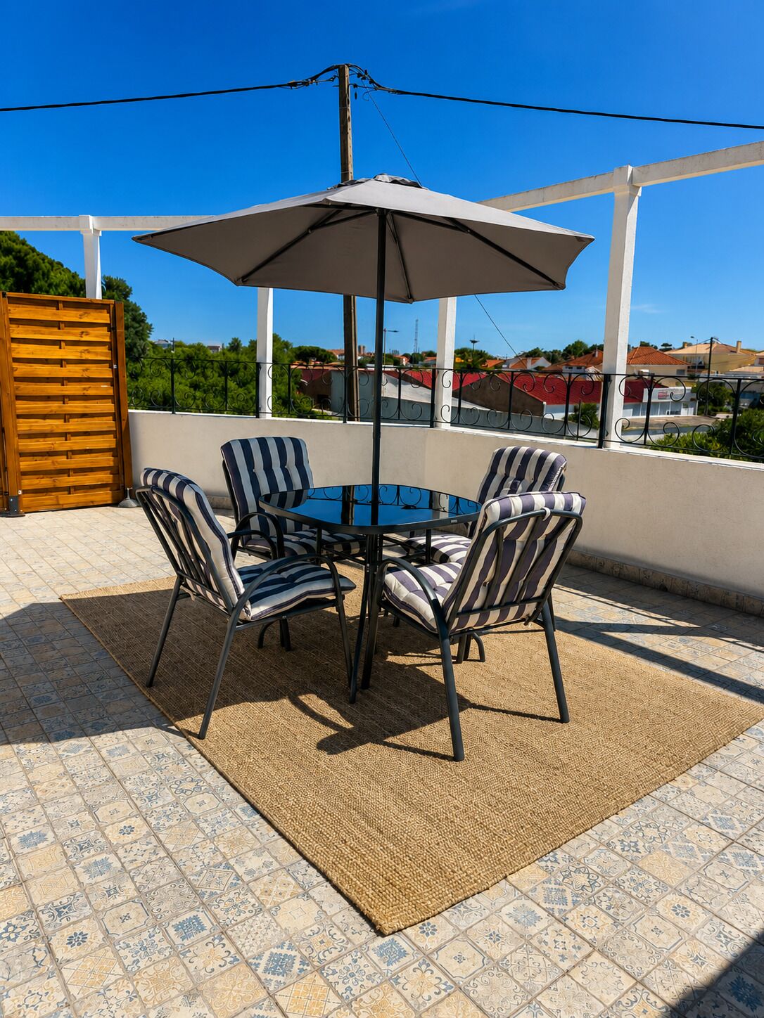 An outdoor patio with a round table, four chairs, and a large umbrella.