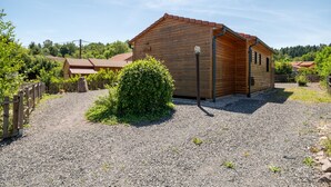 A wooden cabin with a gravel driveway, surrounded by greenery and a wooden fence. - Chalet l'Entékia near Gérardmer with Billiards and Private Spa (Corcieux)