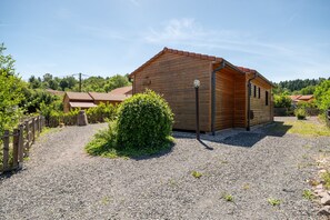 Eine Holzhütte mit Kiesweg, umgeben von Grün und einem Holzzaun.