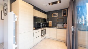 A modern kitchen with light wood cabinets, stainless steel appliances, and a black countertop. - Chalet l'Entékia near Gérardmer with Billiards and Private Spa (Corcieux)