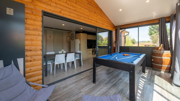 A wooden interior with a pool table, dining area, and large windows. - Chalet l'Entékia near Gérardmer with Billiards and Private Spa (Corcieux)