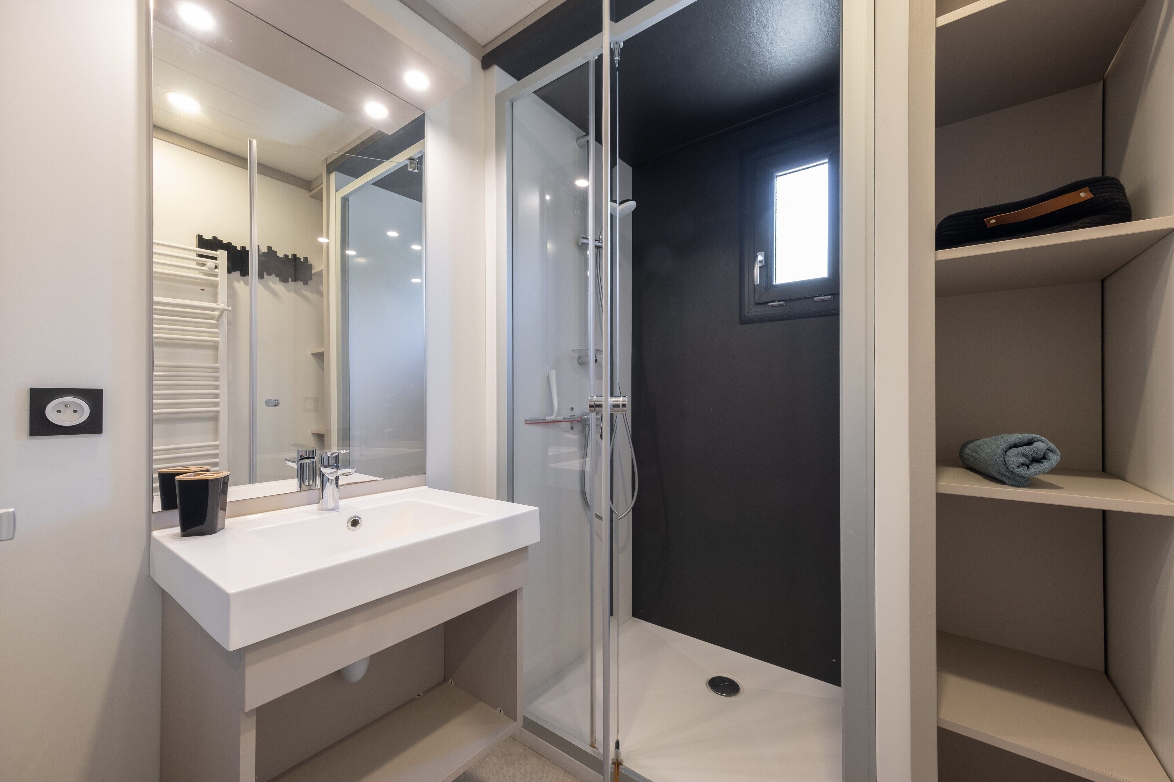 A modern bathroom with a glass-enclosed shower, a white sink, and a mirror.