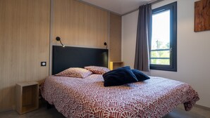A modern bedroom with a large bed, a bedside table, a wall-mounted lamp, and a window with curtains. - Chalet l'Entékia near Gérardmer with Billiards and Private Spa (Corcieux)