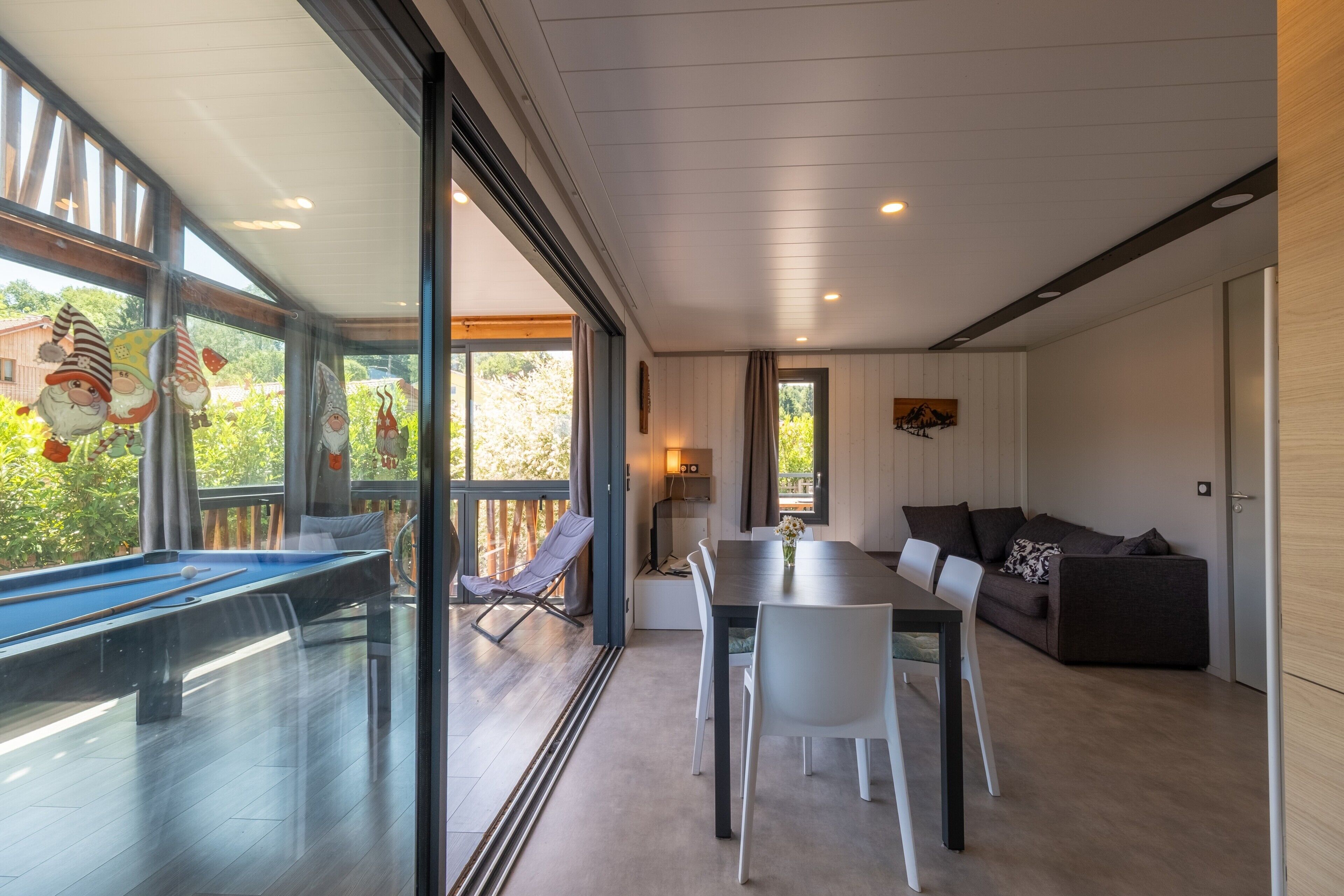 A modern living room with a pool table, a dining table, and a sofa.