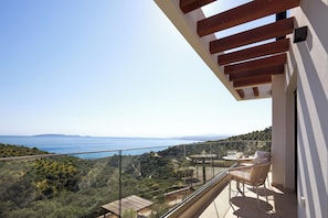 A balcony with a glass railing, a wooden pergola, a table with chairs, and a view of the sea and hills. - Villa Gaia Sea Horizon (Rodia Heraklion)