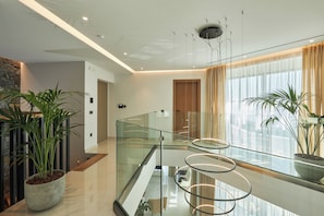 A modern interior with a glass railing, potted plants, and a ceiling light fixture. - Villa Gaia Sea Horizon (Rodia Heraklion)