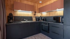 Cozinha moderna com paredes de madeira, armários pretos e painel de fundo de mármore.