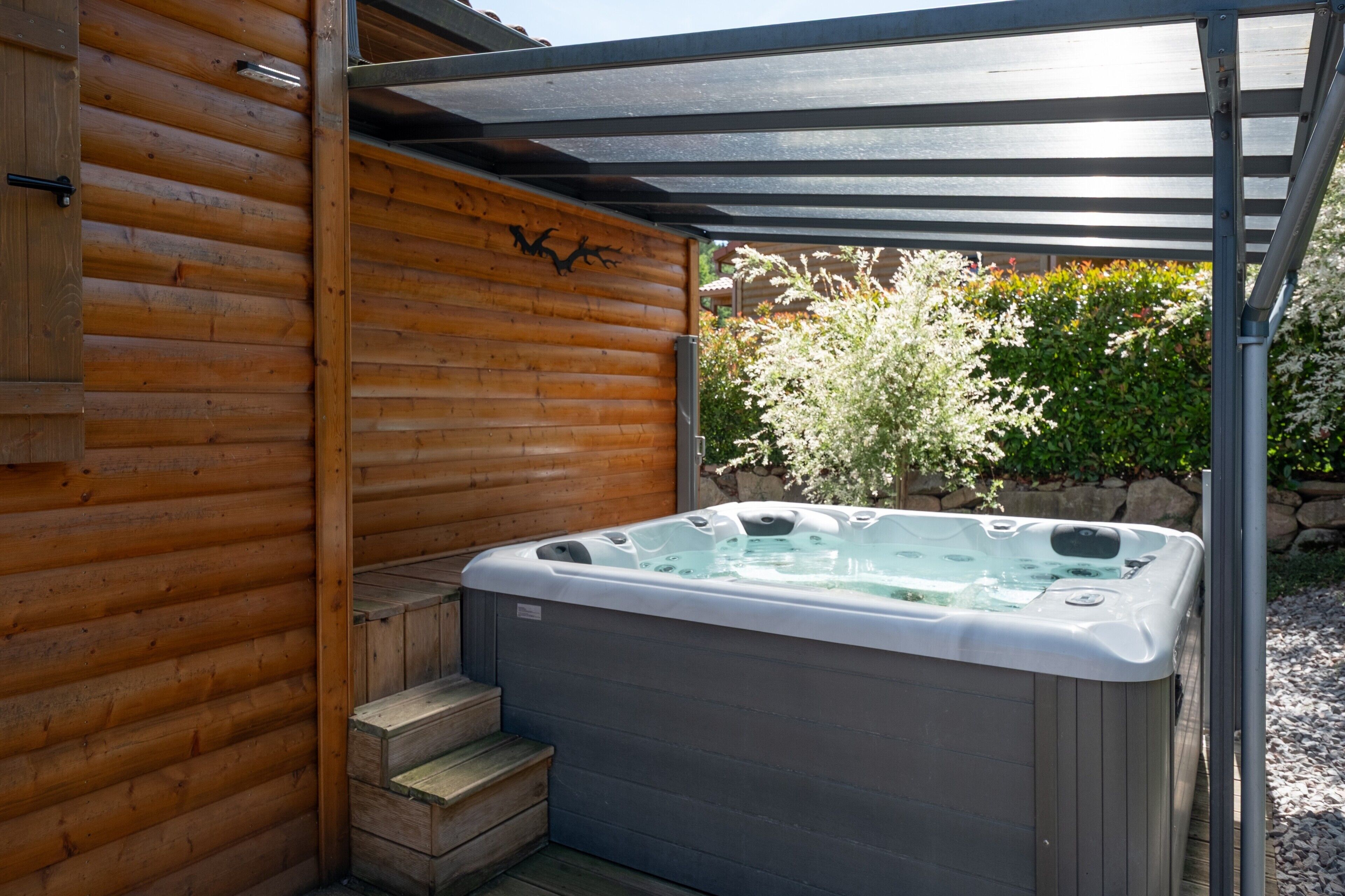 Un bain à remous dans un chalet en bois, surmonté d’une pergola.