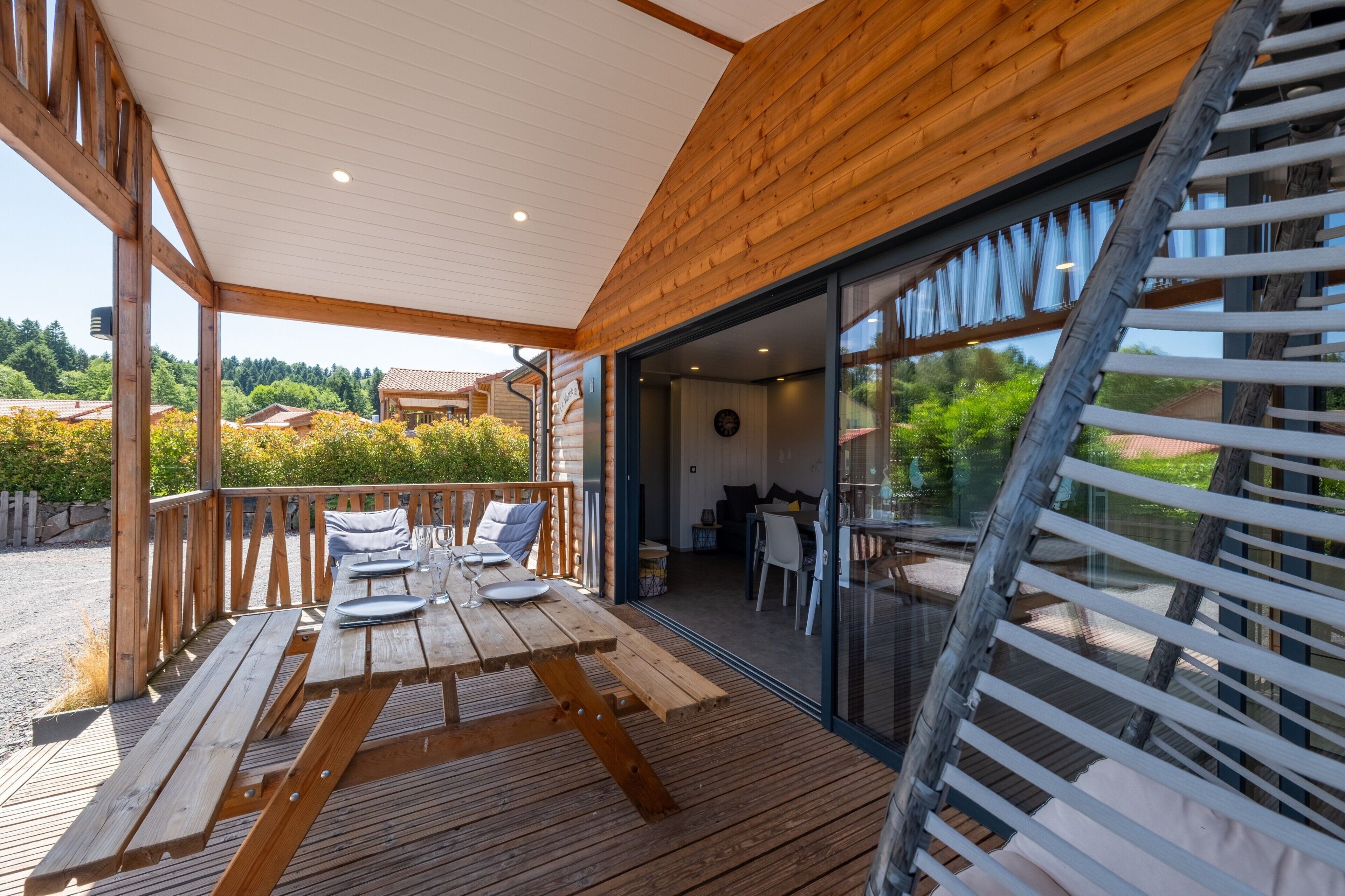 A wooden deck with a table set for dining, a staircase, and a view of the surrounding landscape.