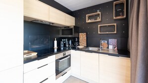 Une cuisine moderne avec un plan de travail noir, des appareils en acier inoxydable et des meubles de rangement en bois.