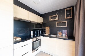 A modern kitchen with a black countertop, stainless steel appliances, and wooden cabinets.