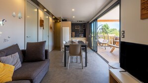Un salon moderne comprenant un canapé, une table à manger, des chaises et un téléviseur.