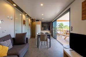 A modern living room with a sofa, dining table, chairs, and a TV.