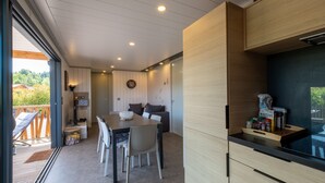 Une cuisine moderne avec des meubles en bois, un coin repas comprenant une table et des chaises, et une vue sur l’extérieur.