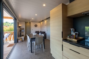 A modern kitchen with wooden cabinets, a dining area with a table and chairs, and a view of the outdoors.