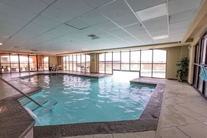 Ein Innenpool mit freiem Blick nach draußen, ein Fliesenboden und eine Decke mit sichtbaren Installationen.