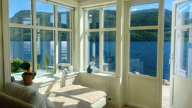 A room with large windows, a bed, a small table, and a potted plant. - Cabin by Telemark Canal with private beach (Høydalsmo)