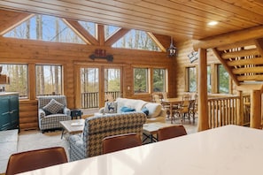 L’intérieur d’un chalet en bois comprend un coin repas, un canapé et un panneau indiquant la présence de pistes de ski.