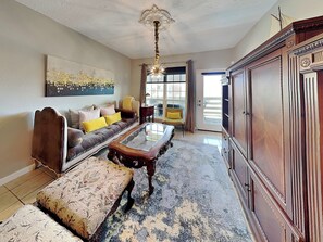 Ein Wohnzimmer mit einer Couch, einem Hocker und einem Couchtisch mit Glasplatte.