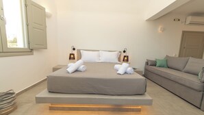 Un dormitorio moderno con cama, lámparas de noche, un sofá y una ventana.