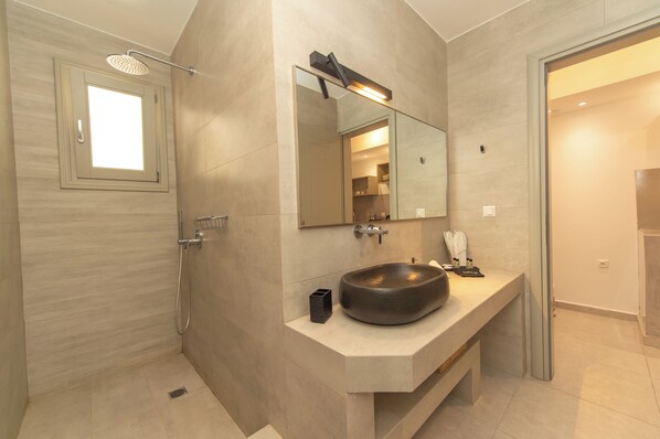Un baño moderno con un espejo grande, un lavabo redondo y una ducha.