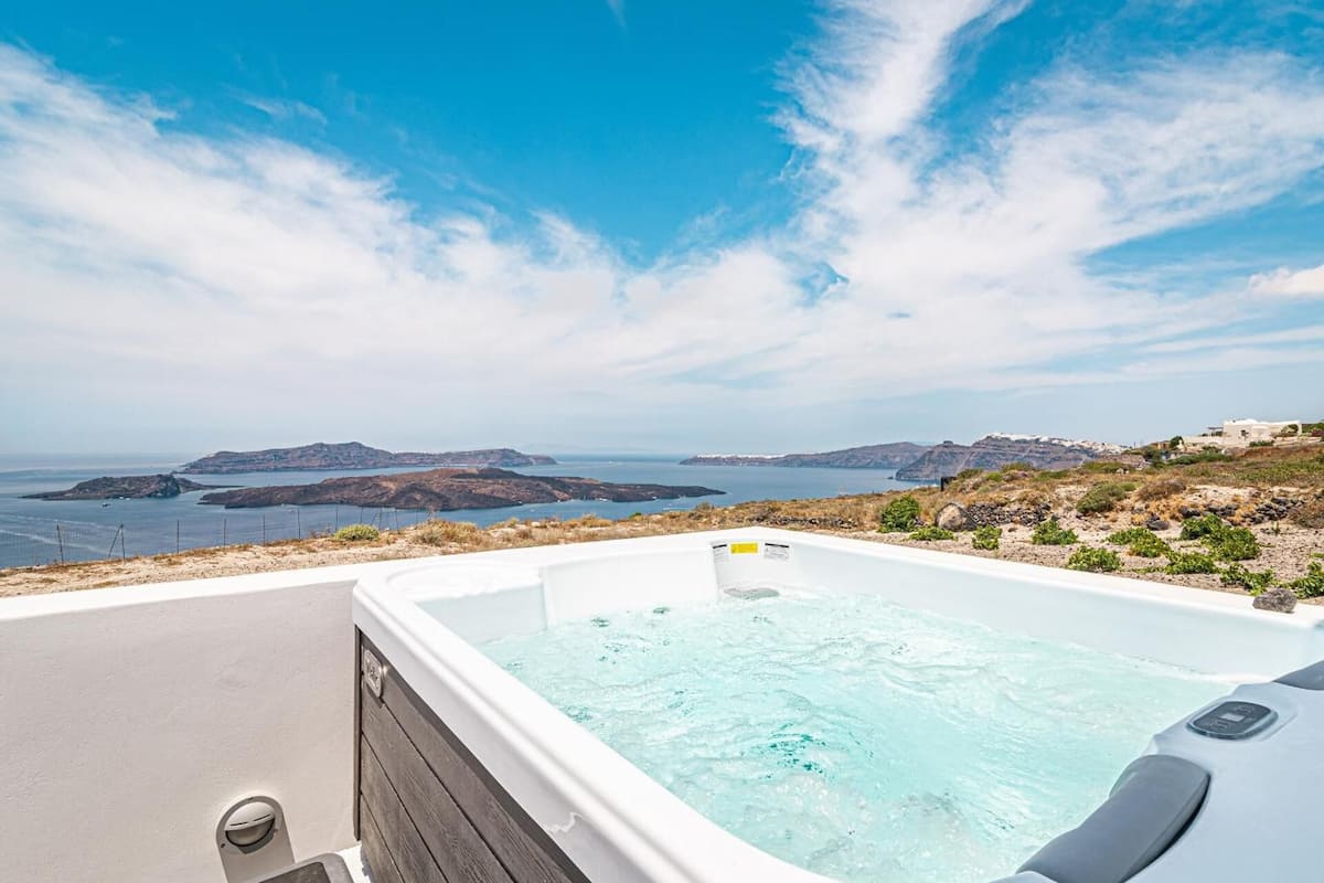 A hot tub with a view of the sea and rocky landscape.