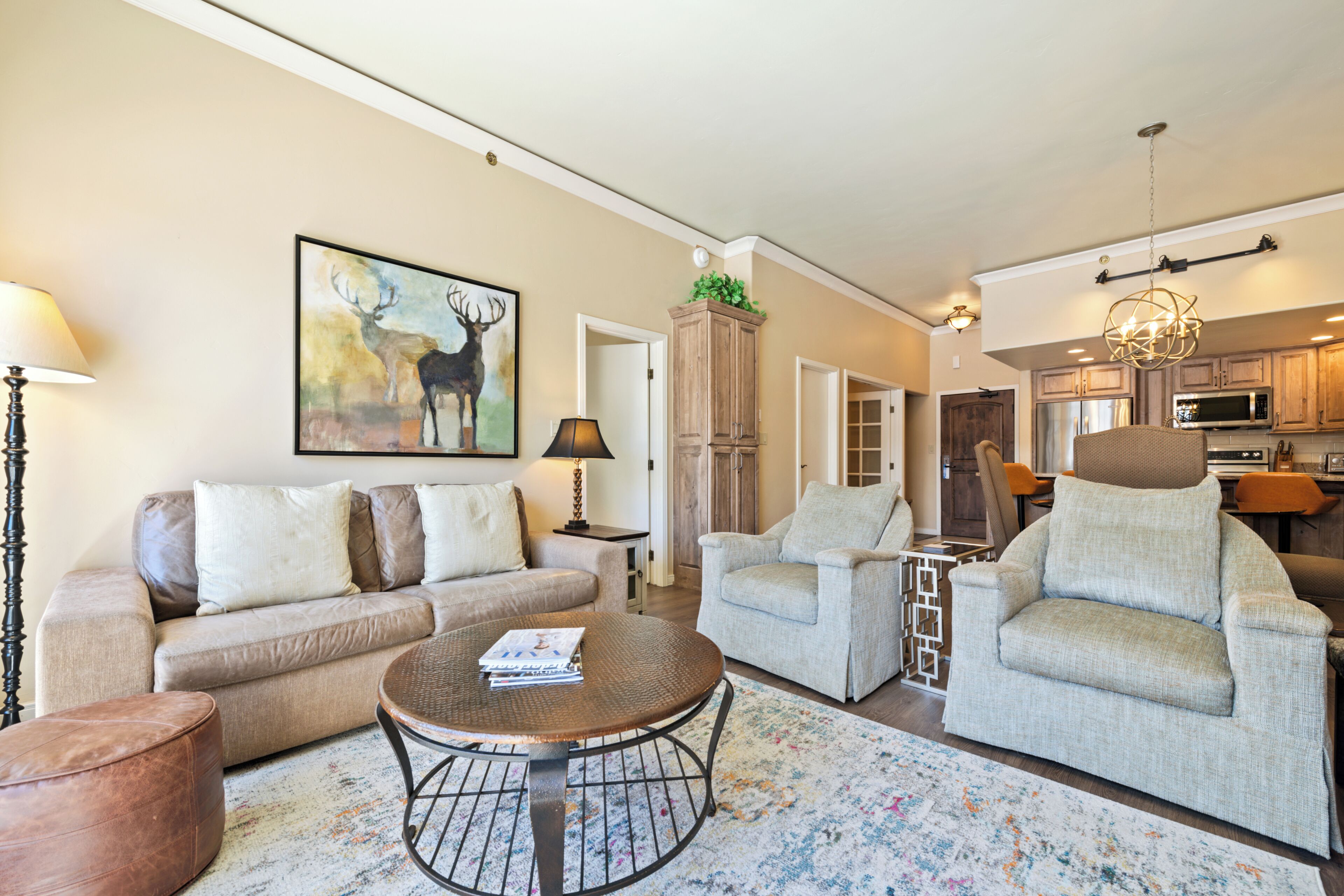 A living room with a sofa, armchairs, a coffee table, and a painting of a deer.