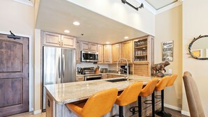 A kitchen with wooden cabinets, stainless steel appliances, a granite countertop, and bar stools. - Beaver Creek Ski-In/Ski-Out Retreat  LB108 (Beaver Creek)