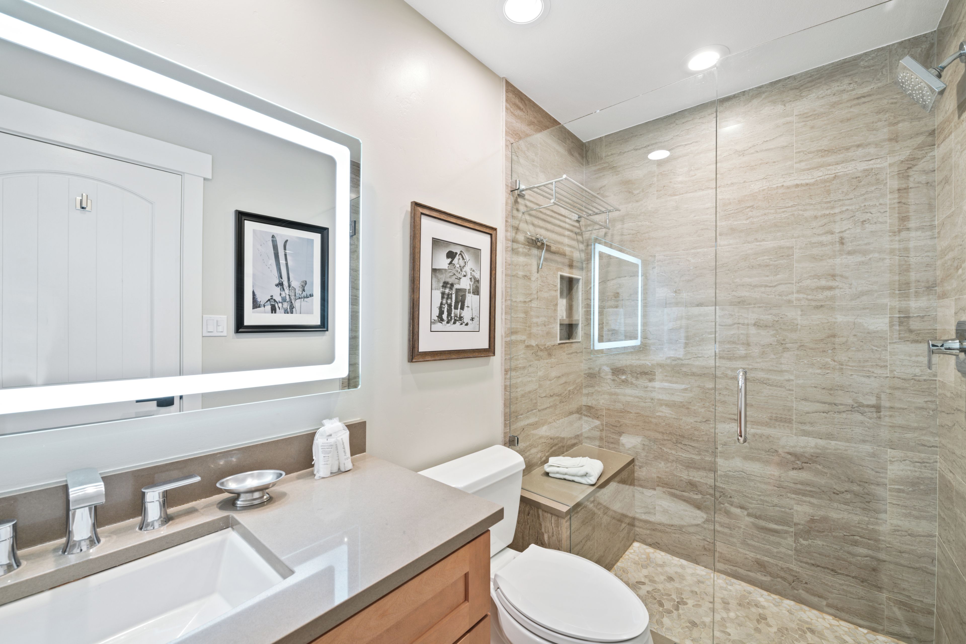 A modern bathroom with a large mirror, a shower enclosure, and a toilet.