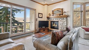 A living room with a fireplace, a television, and a sofa. - Ski-In/Ski-Out, Resort Amenities, Shuttle | LB113 (Beaver Creek)