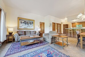 A living room with a sofa, coffee table, rug, and a painting on the wall. - Slopeside Luxury, Pool, Hot Tubs, Conceirge | LB114 (Beaver Creek)